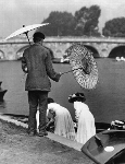 July 1909.  A busy sunshade vendor at Henley waiting whilst the lady punters settle into the punt during the Henley Regatta. Courtesy of HRR - Click for full-size image!